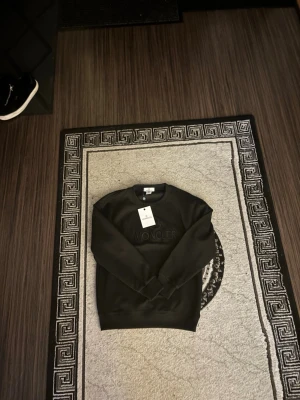 Svart sweatshirt från Moncler - Snygg svart sweatshirt från Moncler med diskret broderad logga på bröstet. Tröjan har rund halsringning, långa ärmar och ribbade muddar vid ärmslut och nederkant. Perfekt för en clean och stilren look.