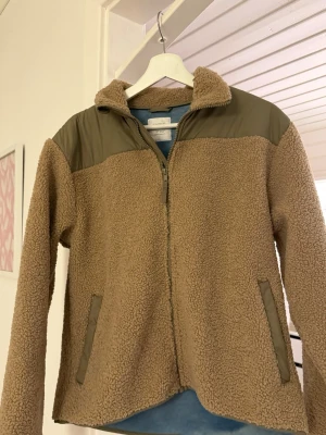Beige teddyjacka - Mysig beige teddyjacka från Lindex med dragkedja framtill. Perfekt för att hålla värmen under kyliga dagar. Tillverkad i mjukt teddy-material. Storlek är kids men passar en S/M 