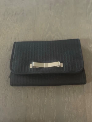 Victoria's Secrets neccesär❤️ - Snygg svart neccesär från Victoria's Secrets med quiltad yta och elegant metallrosett framtill. Insidan har flera fack med dragkedja och genomskinliga sektioner samt små vita prickar på svart botten. Perfekt för att organisera sminken på resan. Superfin❤️