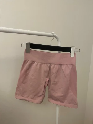 Gym shorts NVGTN - Säljer dessa superfina ljusrosa träningsshortsen från NVGTN🌸ingen scrunch men formar sig jättefint. Storlek S men är stretchiga. Något noppriga i rumpan men inget som förstör💞bara att höra av sig vid funderingar