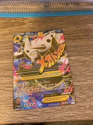 Pokémonkort Mega Aggron EX - Säljer ett färgstarkt och glansigt Pokémonkort: Mega Aggron EX med 240 HP. Kortet har en cool design med svart, gult och rosa motiv samt japansk text. Perfekt för samlare eller dig som vill boosta din lek med ett mäktigt kort.