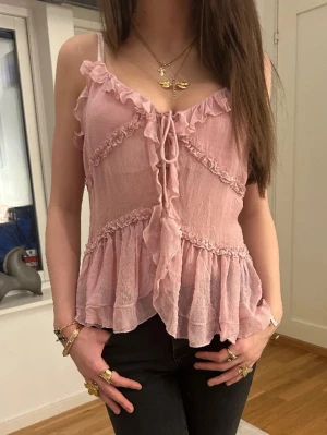 Rosa volangtop från Zara med knyt - Supersöt ljusrosa linnetopp från Zara med volangdetaljer och knyt framtill. Tunt, luftigt material med smala axelband och v-ringning. Perfekt för dig som gillar romantisk och feminin stil.