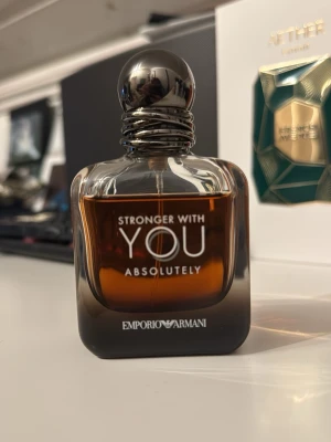 Emporio Armani Stronger With You - Emporio Armani Stronger With You Absolutely är en parfym i en stilren, mörkbrun glasflaska med rundad form och metallisk silverfärgad kork. Flaskan har tydlig logga och text framtill. Doften är intensiv och modern, perfekt för dig som gillar exklusiva parfymer.