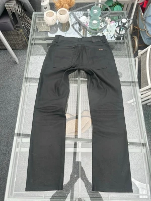 Nudie Jeans svarta – W33 L32 (mycket bra skick) - Säljer ett par stilrena svarta Nudie Jeans i modellen Slim Jim. Perfekta för både vardag och mer uppklätt 👌  • Storlek: W33 L32 • Färg: Svart (dry black coated) • Material: 98% bomull, 2% elastan • Skick: Mycket bra – sparsamt använda • Passform: Slim fit  Snygg coating som ger en clean look, funkar till allt 🔥