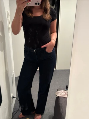 Mörkblå raka jeans - Säljer ett par mörkblå jeans med rak passform och klassisk femficksdesign. Jeansen stängs med knapp och dragkedja. Perfekta till en enkel t-shirt eller hoodie för en clean look.