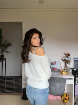 Vit off shoulder tröja - Trendig krämvit off shoulder tröja med avslappnad passform och långa ärmar. Tröjan har bred mudd i nederkant och vid ärmslut, samt en mjuk och lätt ribbad struktur. Perfekt för en chill och stilren look.