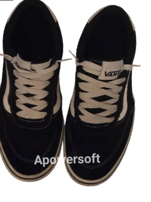 Svarta Vans Old Skool sneakers - Klassiska Vans Old Schooll sneakers i svart mocka och canvas med vita detaljer och den ikoniska sidoranden. Skorna har vita snören och en vit sula med svart rand. Perfekta för en avslappnad streetwear-look.