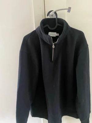 Svart half-zip hoodie från Topman - En svart hoodie från Topman i storlek XS med halv dragkedja framtill. Klassisk och enkel design utan tryck eller mönster, tillverkad i mjukt sweatshirtmaterial. Perfekt för en clean och avslappnad stil.