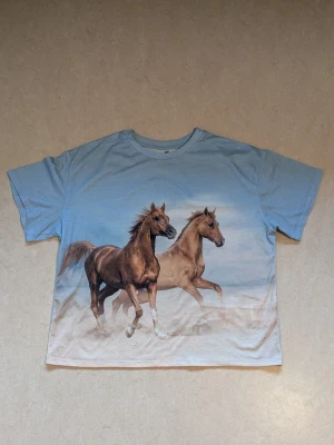 Ljus blå tröja med hästar - Aldrig använd. Jätte fin färg.