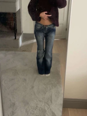 Blå bootcut jeans med slitningar - Snygga blå bootcut jeans med slitningar på knäet och lätt tvättade detaljer. Låg midja. 