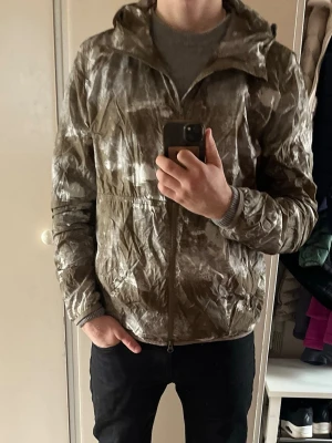 Mönstrad vindjacka från Woolrich - Säljer en tunn vindjacka från Woolrich med brunt och vitt abstrakt mönster.  Jackan är storlek M/L och modellen på bilden är 181 cm.    Nypris 4000