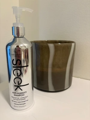 Sleek Anti-Humidity Shampoo - Snygg silverfärgad pumpflaska med Sleek Anti-Humidity Shampoo från Hair Chemist. Schampot hjälper till att skydda håret mot fukt och värme, ger glans och motverkar friss. Perfekt för dig som vill ha superrakt hår.