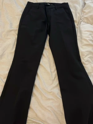 Svarta kostymbyxor från BikBok - Snygga svarta kostymbyxor från BikBok med bootcut klassisk passform. Byxorna har hällor för skärp och diskreta sidofickor. Perfekta för en stilren och trendig look. Materialet känns mjukt och följsamt.