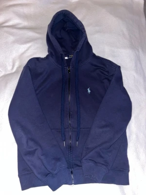 Mörkblå Zip Hoodie från Polo Ralph Lauren - En snygg stilren tröja från Ralph Lauren, funkar till många olika stilar och är perfekt nu till vintern/våren, ett måste i din garderob. Priset går att diskutera skriv vid minsta fundering🤝 Nästan aldrig använd då den är för liten för mig.