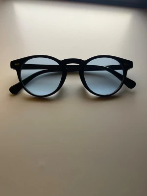 Chimi 03 liknande solglasögon  - Snygga svarta solglasögon med rundad form och blåtonade glas. Klassisk design med bred båge och diskreta silvriga detaljer vid gångjärnen. Perfekta för dig som vill ha en stilren accessoar till sommaren.