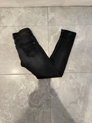 Replay Donny - Snygga svarta jeans från Replay med smal passform och klassisk femficksdesign. Jeansen har subtila slitningar och Replay-logga på bakfickan samt vid myntfickan. Tillverkade i stretchigt denim för extra komfort och stil.