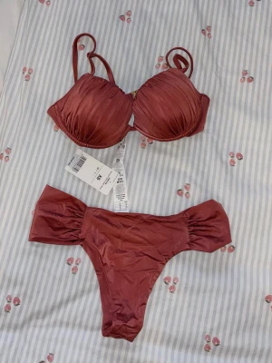 Röd brun bikini calzedonia - Supersnygg bikini från Calzedonia i en röd/brun nyans. Överdelen har vadderade kupor. Så vacker och aldrig använd. Prislapp kvar🫶🏼 Nederdelen är storlek XS och överdel storlek 70D, men skulle säga 70B/70C, pga har själv det och den sitter bra på mig. 300kr för båda delar🩷🩷🩷