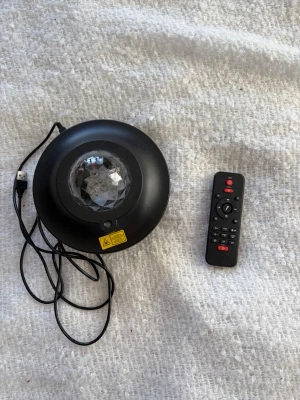 Svart LED projektor med fjärrkontroll - Svart LED projektor. Kommer med USB-sladd och fjärrkontroll för att styra olika ljuslägen. Har även en bluetooth funktion och funkar som högtalare. Bilderna är några exempel på de olika ljuslägerna som finns. Kontakta mig om du har några frågor 😊