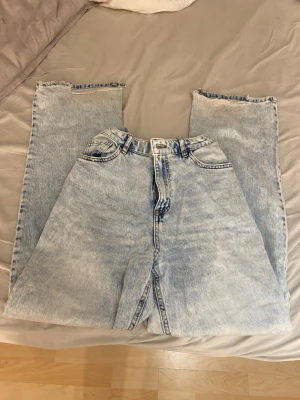 Ljusa baggy jeans med råa kanter - Säljer ett par ljusblå baggy jeans med hög midja och raka ben. Jeansen har råa, avklippta benslut för en trendig och avslappnad look. Klassisk femficksmodell i tvättad denim. Perfekta för dig som gillar streetwear och oversized stil. Passar för xs/xxs/