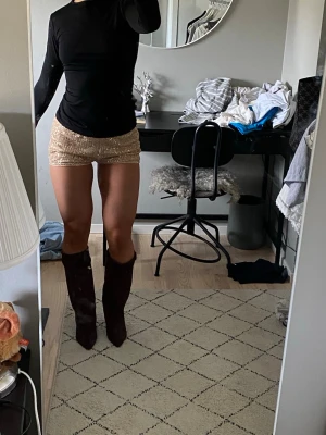 Glittriga paljett shorts - Skitsnygga festshorts i guldglitter. De har paljetter som glittrar och passar bra med höga boots. Storlek S men passar även M, skulle säga att det är onesize. Lågmidjade. Helt nyskick. Köptes på Nelly men hittar ej på hemsidan så tror att de är slutsålda, först till kvarn! 