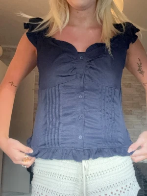 Mörkblå blus med volangdetaljer - Söt mörkblå blus med knappar framtill, kan va både off shouler men också vanligt