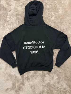 Svart hoodie Acne Studios Stockholm - Svart hoodie från Acne Studios med vit text 