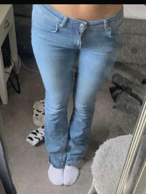 Ljusblå bootcut jeans Lågmidjade - Säljer ett par ljusblå bootcut jeans med klassisk femficksmodell och normal midja. Jeansen har en lätt utsvängd passform nedtill och är tillverkade i mjukt denimtyg. Perfekta för en avslappnad och trendig look.