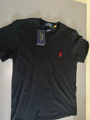 RL Polo T-shirt  - Klassisk svart T-shirt från RL, Stilig design samt även skön tröja. Perfekt till alla tillfällen. För dig som gillar klassiskt och stiliga kläder. Helt ny aldrig använd. Pris kan diskuteras!