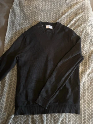 Svart stickad tröja från Selected - Snygg svart stickad tröja från Selected med rund halsringning och ribbade muddar vid ärmslut och nederkant. Enkel och stilren design som passar perfekt till lager-på-lager. Materialet känns mjukt och bekvämt.