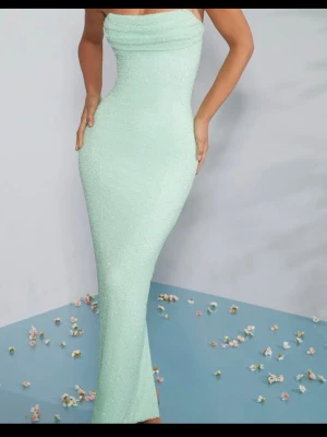 Oh Polly ljusgrön klänning - Supersnygg ljusgrön långklänning med figurnära passform och pärlstruktur. Klänningen är axelbandslös och har en draperad urringning som ger en elegant look. Perfekt för dig som vill sticka ut med en unik och trendig stil. Har använt 1 gång förut.