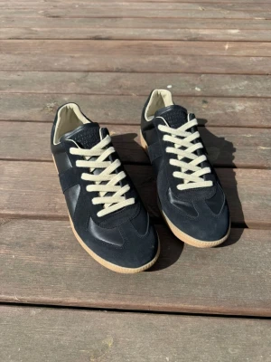 Maison Margiela GATS - Hej, säljer ett par svarta Maison Margiela GATS i storlek 43. De är i god skick, köptes för ett tag sedan men har knappt använt de. De är äkta och inköpsbevis finns. Har inte boxen kvar men dustbag finns. Hör av dig vid intresse eller frågor!