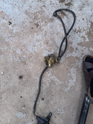 Bromsok med slang till MC eller moped - Säljer ett bromsok i metall med tillhörande bromsslang, troligen till motorcykel eller moped. Färgen är mässing/guld på oket och svart på slangen. Perfekt för dig som behöver reservdelar till ditt fordon.