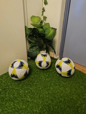 Vita fotbollar med gult och blått mönster - Säljer tre snygga fotbollar i vitt med coolt gult och blått mönster. Perfekta för träning eller spontanfotboll med kompisarna. Bollarna har klassisk rund form och är tillverkade i slitstarkt syntetmaterial.