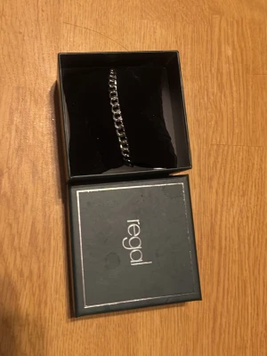 Silverfärgat kedjearmband från Regal - Vet ej vad den kostar så lägger på 299. Pris kan diskuteras. Stilrent armband i silverfärgad metall från Regal. Kedjemodell med klassisk design, levereras i original ask. Perfekt accessoar för att lyfta din outfit med en modern touch.