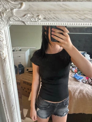 Svart tight t-shirt med kort ärm - En svart, tight t-shirt med korta ärmar och rund halsringning. Enkel och stilren modell som sitter figurnära och passar perfekt till jeans eller shorts. T-shirten är i ett mjukt och stretchigt material.