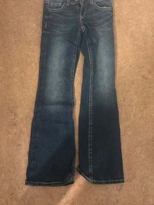 Blå bootcut jeans från Ginatricot - Snygga blå bootcut jeans från Ginatricot med klassisk femficksdesign och markerade sömmar. Jeansen har en lätt tvättad look och vida ben nedtill. Perfekta för dig som gillar en retrostil och vill ha ett par jeans som sticker ut.