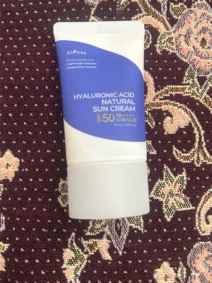 Isntree Hyaluronic Acid Sun Cream - Solkräm med SPF 50+ från Isntree. Innehåller hyaluronsyra som återfuktar huden och skyddar mot UVA/UVB. Tuben är vit med blå etikett och har en smidig, kompakt form som är lätt att ta med i väskan. Bara testade