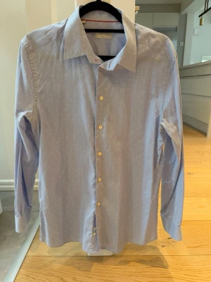 Eton Slim Fit Skjorta 42 Super Slim – Kanonskick & Stilren 👔 - Ljusblå Eton-skjorta i supersnygg slim fit-modell med subtilt prickigt mönster. Storlek 42 Super Slim, motsvarar ungefär 39 Slim Fit. Perfekt för både kontor och mer uppklädda tillfällen.  Skjortan är i kanonskick och sparsamt använd.✔️ Djur- och rökfritt hem✔️ Stilren och tidlös modell✔️ Bekväm passform med elegant silhuett  Säljes då den tyvärr inte kommer till användning längre.