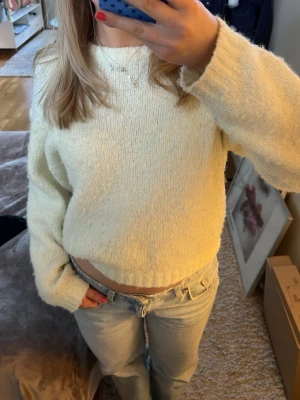 Krämvit stickad cropped tröja - Mysig ljusgul stickad tröja med croppad passform och är perfekt att matcha med jeans för en somrig look.