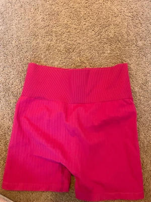 Rosa ribbade shorts från H&M - Säljer ett par snygga rosa shorts från H&M i storlek XS. De är ribbade med hög midja och har en tight passform. Perfekta för dig som gillar färgglada och bekväma plagg till sommaren.
