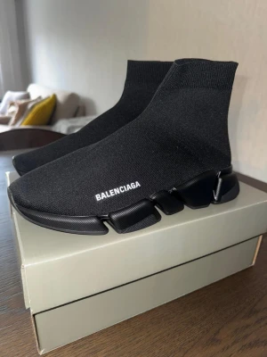 Balenciaga Speed Trainer svarta sneakers - Svarta Balenciaga Speed Trainer sneakers med stickad ovandel i stretchigt tyg och chunky sula. Minimalistisk design med vit logga på sidan och ribbad kant vid ankeln. Snygga och futuristiska skor som sticker ut.