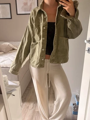 Olivgrön jeansjacka från Zara XS - Snygg olivgrön jeansjacka från Zara i storlek XS. Jackan har två stora fickor framtill, klassisk krage och knäppning med silvriga knappar. Perfekt oversized passform för en avslappnad look.