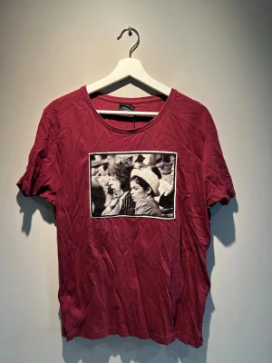 Vinröd t-shirt med tryck från Limitato - Cool vinröd t-shirt från Limitato med ett svartvitt foto-tryck på bröstet. T-shirten har rund halsringning och korta ärmar. Perfekt för dig som vill sticka ut med en unik printad tee.Storlek L Unisex