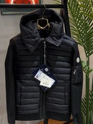 Svart pufferjacka från Moncler - Snygg svart pufferjacka från Moncler med quiltad front och huva. Jackan har stickade ärmar, dragkedja framtill och fickor med dragkedja. Moncler-logga på ärmen och en extra ficka med dragkedja på vänster arm. Perfekt för kalla vinterdagar.