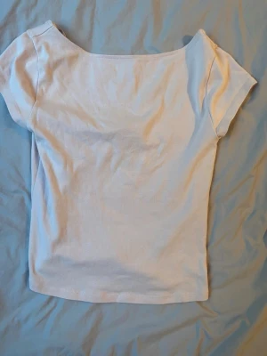 Vit kortärmad topp med rund hals - En basic vit topp med korta ärmar och rundad halsringning. Perfekt att styla med jeans eller kjol. Tillverkad i mjukt bomullsmaterial för en skön känsla hela dagen.