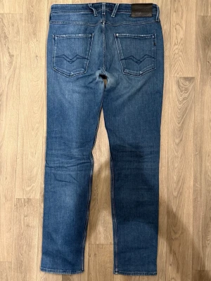 Replay Anbass Jeans Blå W33/L32 - Slim Fit - Replay Anbass blå jeans i stretchig denim med slim fit passform som sitter snyggt och bekvämt och funkar till allt, storlek W33/L32, midja 43 cm, ytterbenslängd 106,5 cm, benöppning 16,5 cm, modellen är 185cm & väger 65kg, i fint skick.