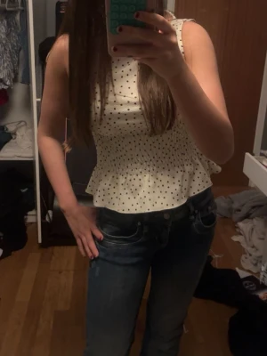 Vit prickig ärmlös blus med volang - Jättesnygg kortärmad blus med prickar från Gina. Använd 1 -2 gånger. Nytt skick
