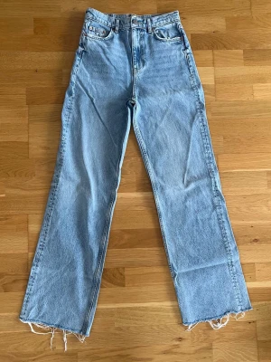 Ljusblå raka jeans med råa kanter - Säljer ett par ljusblå jeans med rak passform, hög midja och fransiga benslut