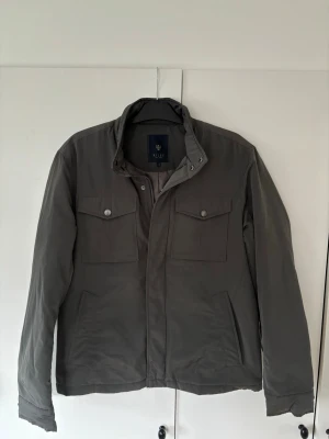 Riley field jacket herr 52 - Jättefin populär trendig elegant mörkgrön glänsande Riley fieldjacket i storlek 52 säljes. Utmärkt skick knappt använd något alls så riktigt kap! Sjukt snygg på, grym passform och perfekta jackan för alla tillfällen. Nypris på ca 2000 och går ej att få tag på längre.