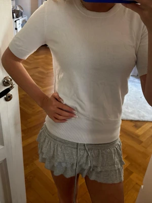 Vit kortärmad topp från Zara - En enkel och stilren vit topp från Zara med korta ärmar och rund hals. Toppen är gjord i mjukt material och har ribbade detaljer vid ärmslut och nederkant. Perfekt att matcha med både jeans och kjol.